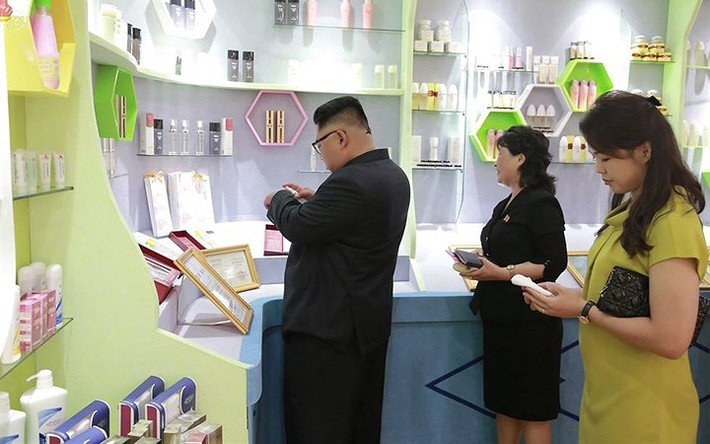 Ông Kim Jong-un thử mỹ phẩm của nhà máy sản xuất lên tay.