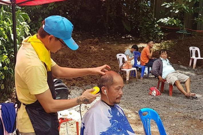 Tình nguyện viên cắt tóc gần hang Tham Luang. Ảnh: ABC.