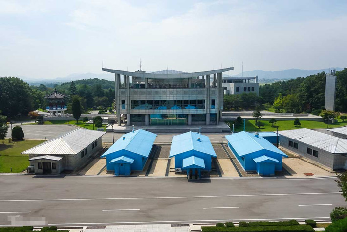 Những lều màu xanh của Liên Hợp Quốc tại Khu An ninh chung, nơi đây có kê 1 chiếc bàn gỗ dọc theo tuyến biên giới hai nước.