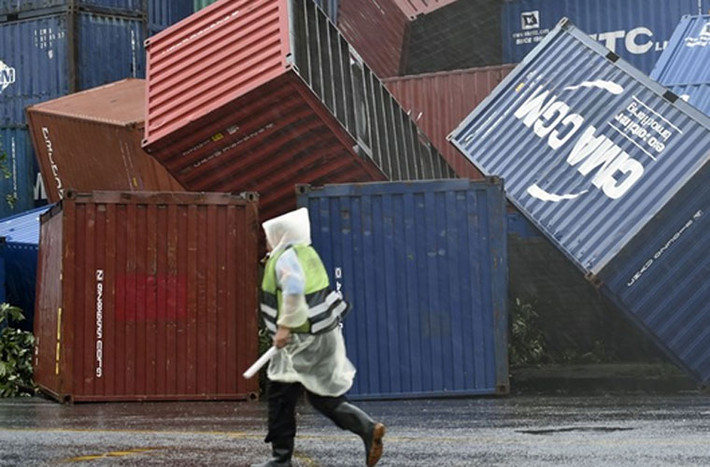 Người đàn ông đi ngang qua các container chở hàng bị đổ lộn xộn ở cảng Kaohsiung.