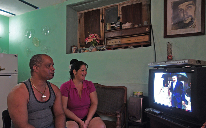 Hai vợ chồng sinh sống ở La Habana theo dõi ti vi đang chiếu bản tin nói về chuyến thăm lịch sử Cuba của Tổng thống Obama.