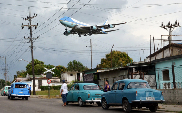 Hai người dân Cuba đỗ xe để chứng kiến cảnh chuyên cơ Không lực Một chở Tổng thống Obama tới Cuba đang hạ cánh xuống sân bay.