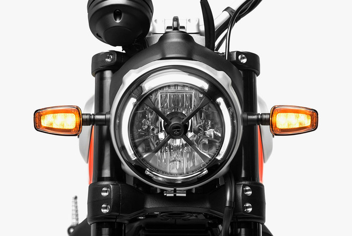 Thay đổi ở hệ thống đèn chiếu sáng trên Scrambler 2019 là điểm dễ nhận ra nhất. Bên cạnh đèn pha được mạ chrome bên ngoài, xe còn sở hữu thêm đèn LED định vị được bố trí viền tròn theo chóa đèn pha đi kèm khung chữ X màu đen lấy cảm hứng từ những mẫu xe đua ở thập niên 1970. Đèn xi-nhan cũng được thay bằng đèn công nghệ LED.