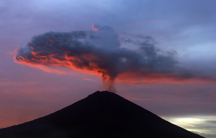 Núi lửa Agung trên đảo Bali, Indonesia phóng cột tro bụi lên độ cao 4.000 m khi phun trào hôm 25/11 khiến hàng chục nghìn người rời bỏ nhà cửa, hàng nghìn du khách không thể về nhà do hàng trăm chuyến bay bị hoãn. Ảnh: AP.