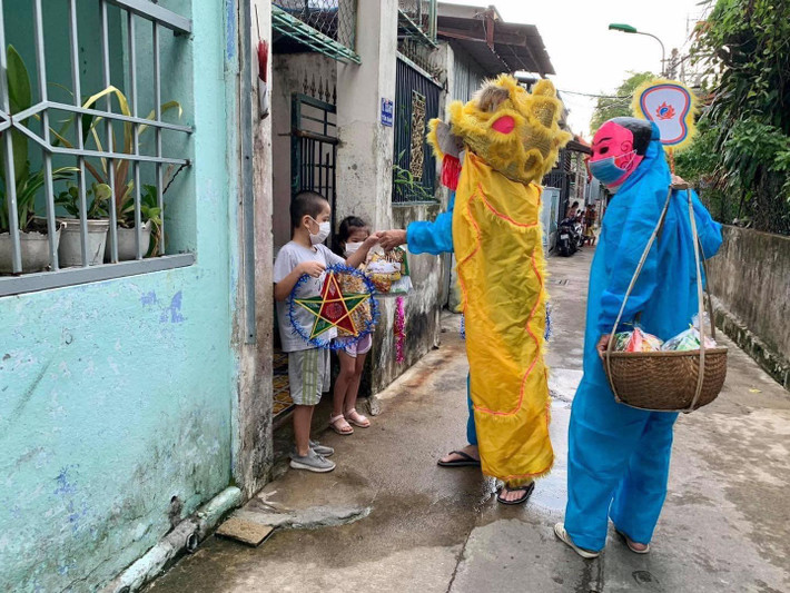 Thay vì khoác lên mình trang phục múa lân hay ông địa đúng nghĩa, những tình nguyện viên lại khoác lên mình đồ bảo hộ chống dịch. Ảnh: Trương Vĩnh Đặng
