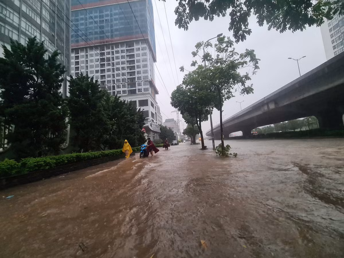 Đường Phạm Hùng ngập sâu, người dân phải dắt bộ xe trên vỉa hè.