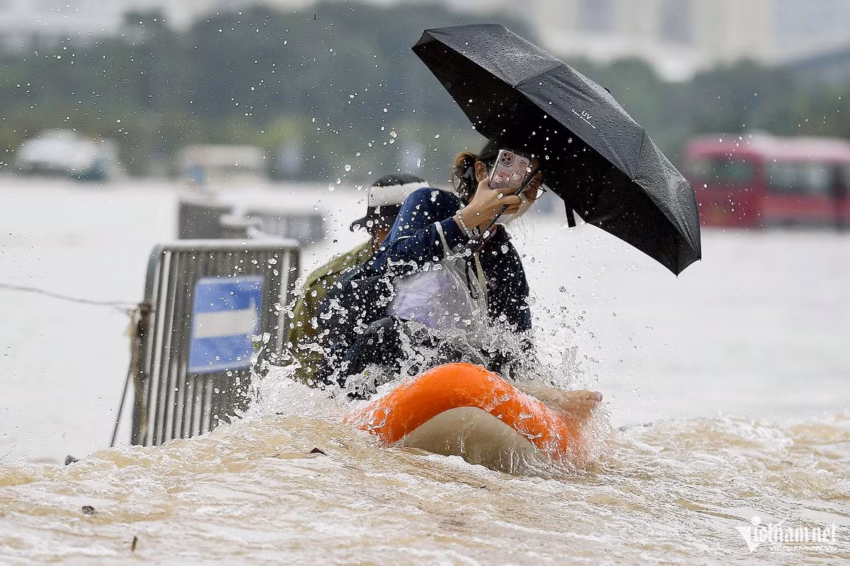 Một người đàn ông chèo thuyền hơi hỗ trợ người dân qua đoạn ngập sâu trên đường Lê Quang Đạo, đoạn trước cửa sân vận động Mỹ Đình.