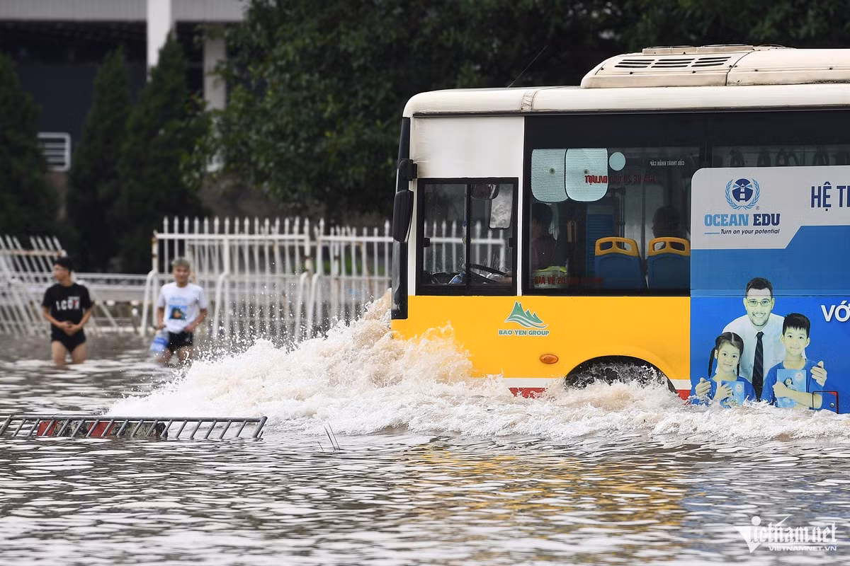 Tài xế xe buýt tăng ga phóng thật nhanh để không bị nước tràn vào ống xả, đã tạo làn sóng đánh rất mạnh về hai bên đường. Một số thanh niên xắn quần cao để đi lại.