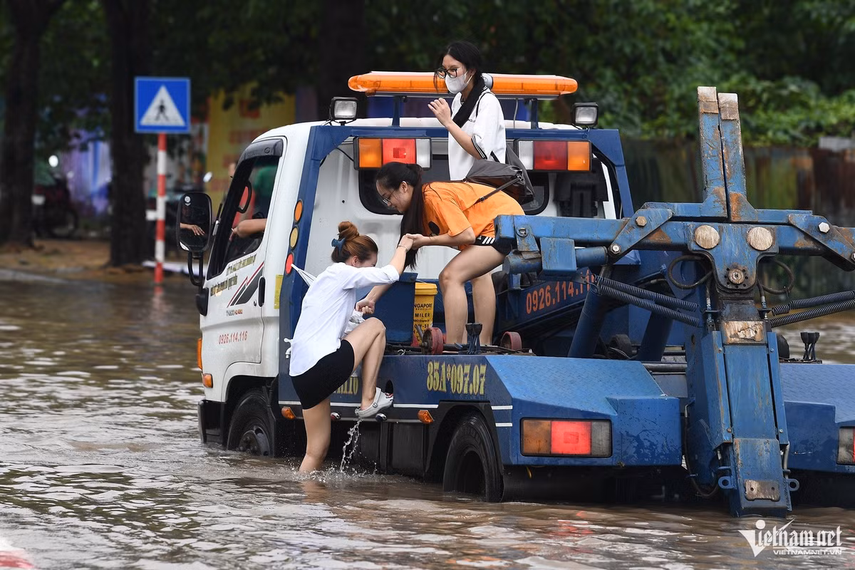 Ba cô gái được một tài xế xe cứu hộ cho đi nhờ qua đoạn ngập trên đường Lê Quang Đạo.