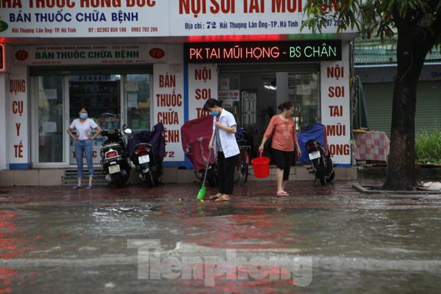 Nhiều người dân ở đường Hải Thượng Lãn Ông thu dọn nhà, vỉa hè sau khi nước ngập đường.