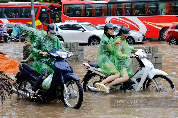 Không thể di chuyển dưới lòng đường vì ngập sâu, một số phương tiện xe máy đi trên vỉa hè vấp phải vật liệu xây dựng nên phải xuống xe dắt bộ.
