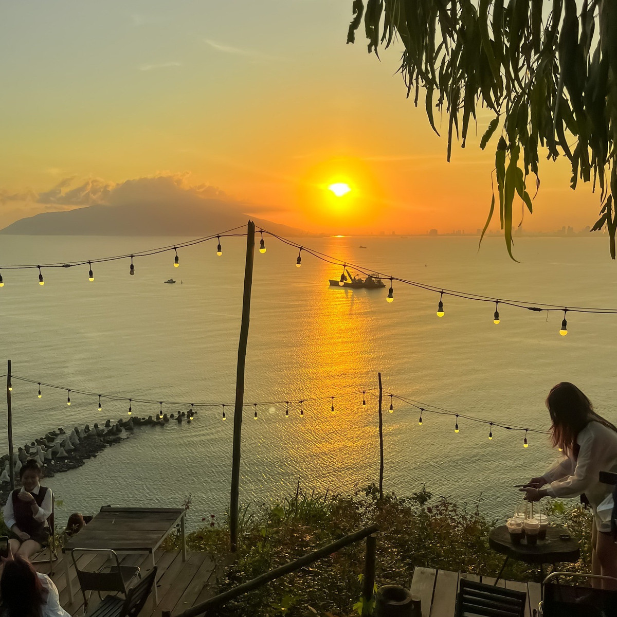 Nằm nép mình giữa sườn đèo, V – Village Hải Vân sở hữu tầm nhìn ôm trọn biển Lăng Cô và những dãy núi trùng điệp. Không gian quán được thiết kế mở, sử dụng gỗ và vật liệu tự nhiên làm chủ đạo, tạo cảm giác vừa ấm cúng, vừa phóng khoáng. Ảnh Fanpage V – Village Hải Vân