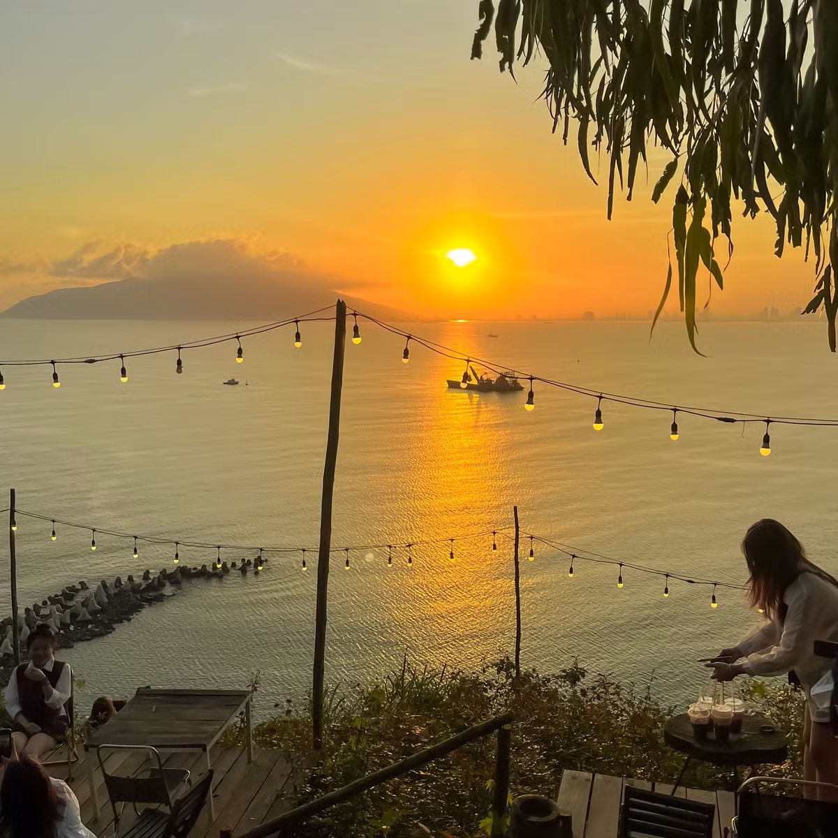 Nằm nép mình giữa sườn đèo, V – Village Hải Vân sở hữu tầm nhìn ôm trọn biển Lăng Cô và những dãy núi trùng điệp. Không gian quán được thiết kế mở, sử dụng gỗ và vật liệu tự nhiên làm chủ đạo, tạo cảm giác vừa ấm cúng, vừa phóng khoáng. Ảnh Fanpage V – Village Hải Vân