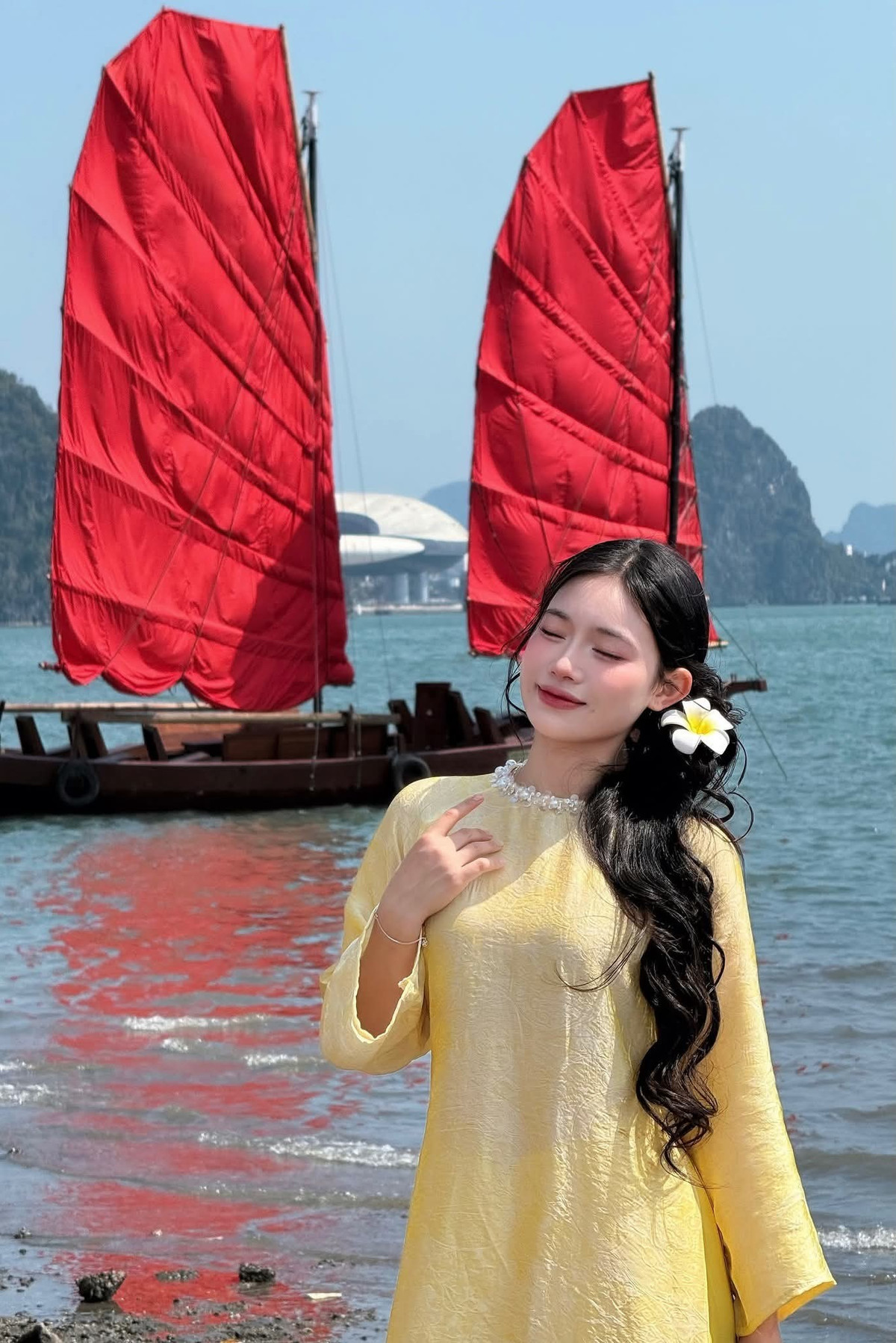 Sự kết hợp giữa tà áo bay nhẹ trong gió và cánh buồm đỏ phía xa tạo nên những khung hình đậm chất nghệ thuật, dễ dàng gây “bão” mạng xã hội. Ảnh Thanh Huyền