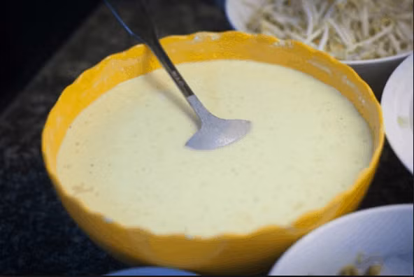 Để chuẩn bị bánh khọt tại nhà, bạn cần các nguyên liệu: 300 g tôm tươi, 100 g thịt nạc băm, 200 g mực tươi, 250 g bột gạo, 50 g bột chiên giòn, 70 g cơm, 200 ml nước cốt dừa, 200 ml nước dừa tươi, nấm mèo, hành tím, tỏi, hành lá, ớt hiểm, 10 g bột nghệ, 1 muỗng canh bột năng, 1 quả trứng gà và các loại rau ăn kèm như cải bẹ xanh, rau thơm, húng quế, diếp cá, xà lách. Ảnh minh họa