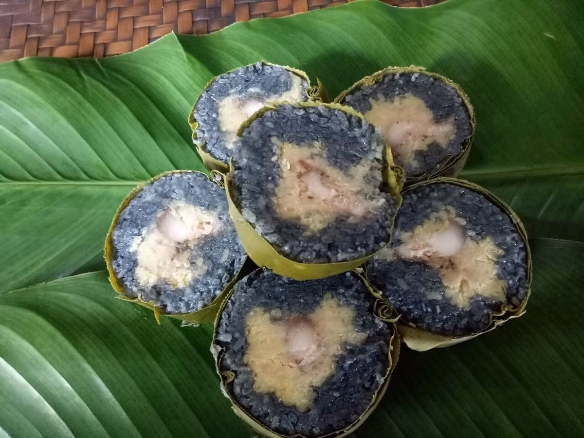 Một món bánh khác cũng khiến du khách thích thú là bánh chưng đen hay còn gọi là bánh chưng đôi. Màu đen tự nhiên của bánh được tạo nên từ cây núc nác hoặc hoa vừng đen, hòa cùng nếp Tú Lệ nổi tiếng. Khi cắt ra, phần gạo đen óng quyện lớp đậu xanh vàng ươm, thịt lợn rừng thơm nức, dẻo quánh mà không ngấy. Ảnh MIA