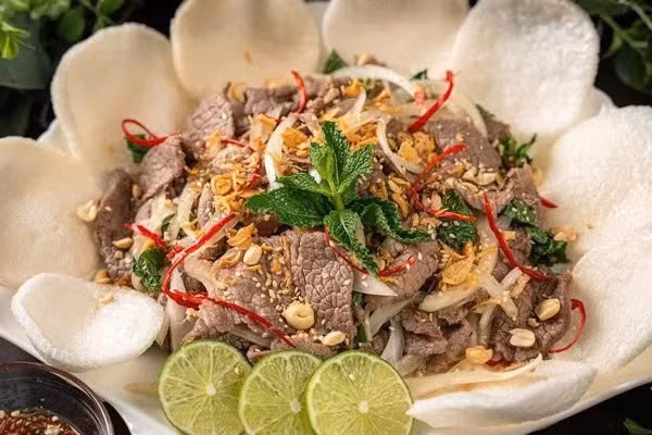 Món ăn thường được chế biến từ thịt bò thái lát mỏng, kết hợp với hành tây, tỏi, hành tím, ớt và nhiều loại rau thơm như mùi, ngổ, tía tô, bạc hà. Thịt bò được nêm muối, tiêu, nước dùng gà, sau đó trộn cùng nước cốt chanh hoặc chanh xanh và một chút đường để cân bằng vị chua. Độ axit của chanh giúp làm tái thịt bò một cách tự nhiên, không cần qua nhiệt, tạo nên hương vị đặc trưng khó trộn lẫn. Ảnh minh họa