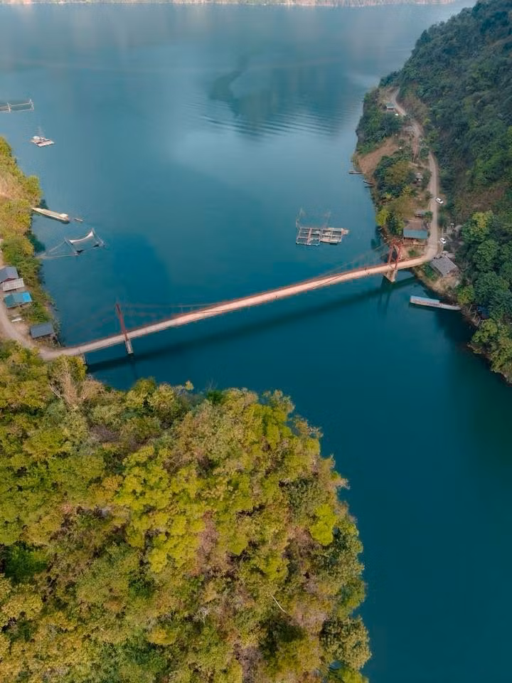 Từ trên cao nhìn xuống, Pa Phông hiện lên như một bức tranh thủy mặc. Hai bên là những dãy núi đá vôi sừng sững, phủ xanh bởi rừng cây đại ngàn, phía dưới là làn nước trong veo mang sắc xanh ngọc bích. Cây cầu mảnh mai lơ lửng giữa không trung, nối liền hai bờ vách đá khổng lồ, vừa hùng vĩ vừa nên thơ.