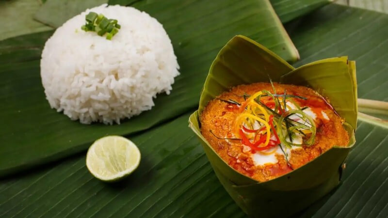 Khi nhắc đến ẩm thực xứ Chùa Tháp, khó có thể bỏ qua fish amok – món ăn được xem như biểu tượng quốc gia. Cá tươi được nấu cùng nước cốt dừa, trứng và hỗn hợp gia vị kroeung gồm sả, riềng và nghệ, sau đó hấp trong lá chuối. Thành phẩm có vị béo nhẹ, thơm nồng nhưng không ngấy, phản ánh sự tinh tế trong cách nêm nếm của người Khmer. Ảnh Traveloka