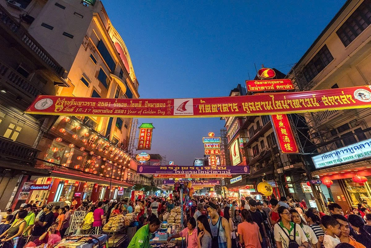 Khi màn đêm buông xuống, Yaowarat – khu Chinatown trứ danh – gần như không có khoảng lặng. Ánh đèn neon rực rỡ phủ kín các dãy phố, mùi khói bếp bốc lên từ hàng chục quầy nướng, xào, chiên sát vỉa hè, hòa lẫn tiếng người gọi món và bước chân du khách. Ảnh TAT