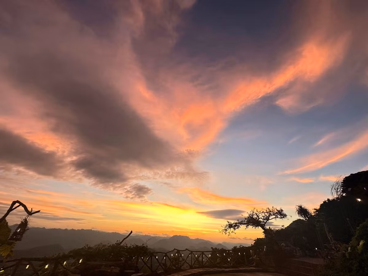 Không chỉ hấp dẫn vào buổi sớm, đỉnh Mu Náu còn là điểm ngắm hoàng hôn được nhiều du khách yêu thích. Từ khoảng 16h30, khi mặt trời dần khuất sau các dãy núi, bầu trời chuyển sang những gam màu cam, hồng, tím rực rỡ, phản chiếu lên mây và rừng núi tạo nên khung cảnh đầy cảm xúc. Ảnh Tiệm cà phê Mu Náu Ơi