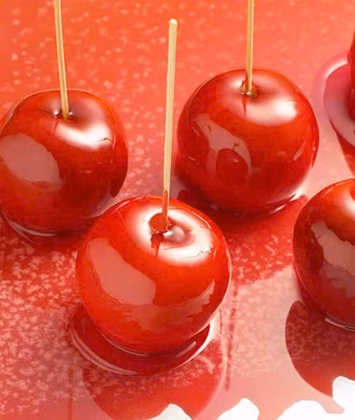 Khi caramel đã tan hoàn toàn, nhấc nồi ra và để nguội bớt cho đến khi hỗn hợp còn ấm. Đây là nhiệt độ lý tưởng để caramel bám đều lên bề mặt táo mà không bị chảy loang. Nhẹ nhàng nhúng từng quả táo vào nồi caramel, xoay đều tay để lớp kẹo bao quanh bóng mượt. Ngay sau đó, lăn táo qua bát đậu phộng hoặc hạnh nhân giã nhỏ để tạo lớp topping giòn rụm hấp dẫn. Ảnh minh họa