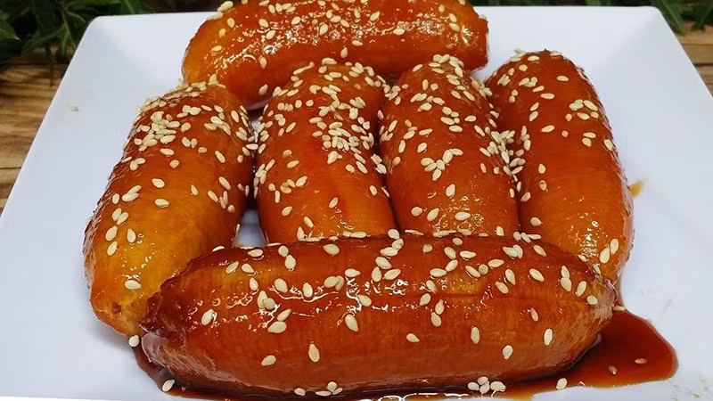 Người miền Tây vốn coi chuối là “nguyên liệu vàng” của ẩm thực quê nhà. Từ món chuối nếp nướng thơm phức, bánh chuối chiên giòn tan, đến chuối hấp cốt dừa ngọt lịm – tất cả đều là món quà gắn liền với tuổi thơ của bao người. Và chuối ngào đường là một trong những biến tấu mộc mạc mà đặc biệt nhất. Ảnh minh hoạ