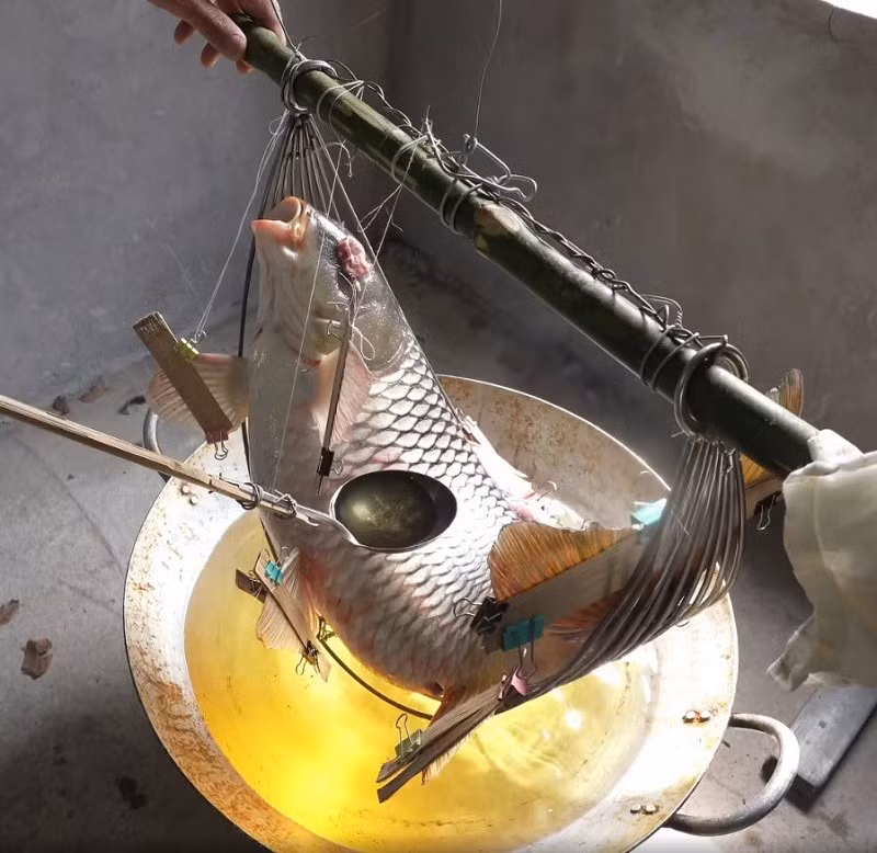 Công đoạn chiên cá đòi hỏi kỹ năng cao và sự tỉ mỉ: chiếc chảo sâu lòng được đổ khoảng 5 lít mỡ lợn, cá đặt giữa chảo, người chế biến dùng muôi múc mỡ đang sôi rưới lên toàn thân cá cho đến khi vàng đều. Ảnh FB Street Food