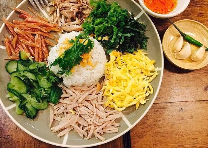 Một đĩa cơm Âm phủ điển hình gồm cơm trắng được xới nóng đặt ở giữa, xung quanh là các thành phần như chả lụa thái sợi, thịt rim, trứng chiên sợi, nem chua, tôm luộc, đồ chua, dưa leo, rau thơm… Tất cả được xếp vòng tròn đầy màu sắc, tạo nên một bố cục cân đối và cuốn hút. Thêm chút mỡ hành, một chén nước mắm pha chua ngọt đúng điệu, vậy là đã có ngay một món ăn vừa ngon vừa đẹp.