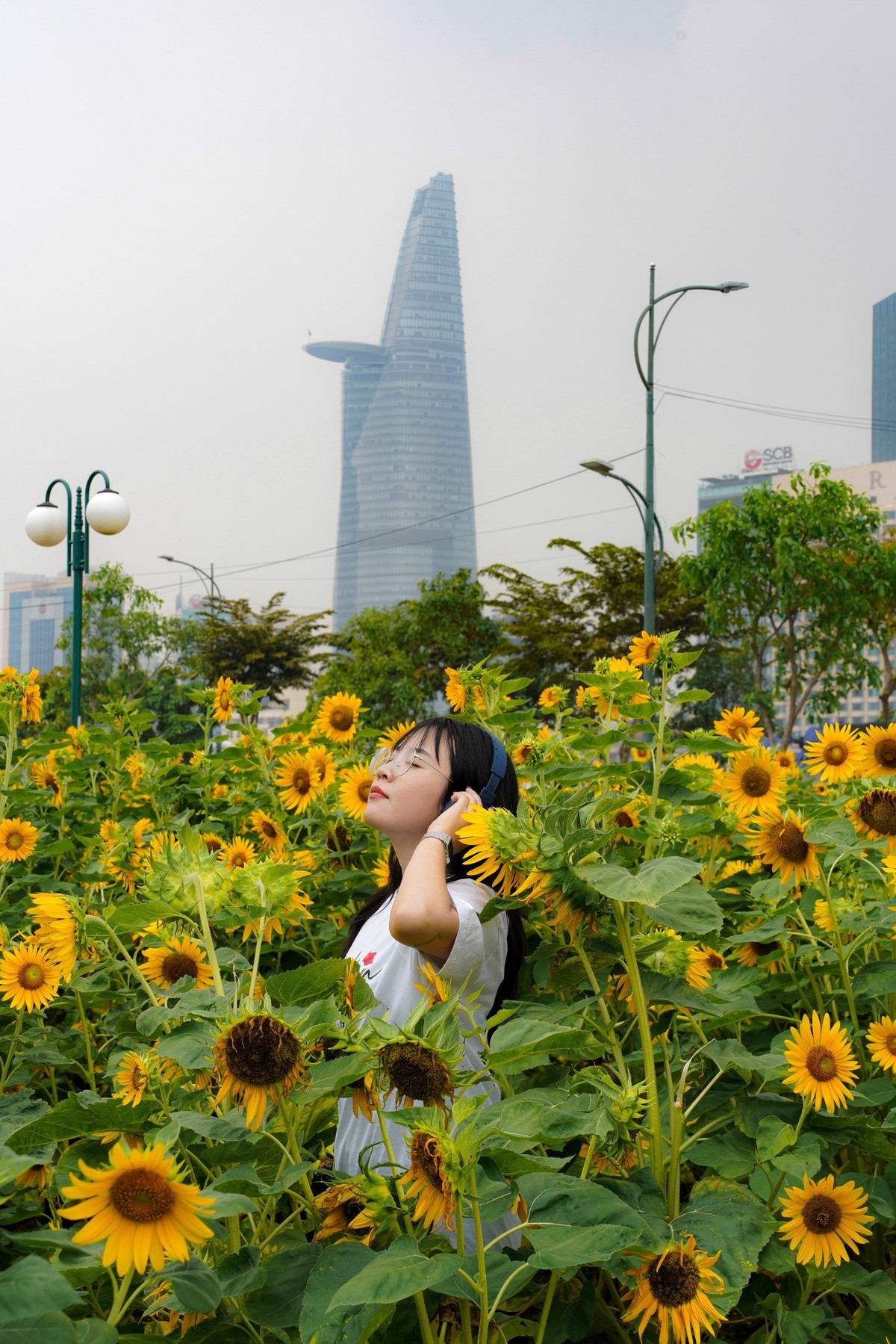 Một số du khách trẻ chia sẻ, ngoài chụp hình, họ còn thử nhiều góc máy khác nhau, từ cận cảnh các bông hoa vàng rực rỡ đến toàn cảnh vườn hoa kết hợp với dòng sông và những tòa nhà cao tầng xa xa. Không gian mở và ánh sáng tự nhiên giúp họ có những bức ảnh sống động, mang cảm giác vừa hiện đại vừa gần gũi với thiên nhiên. Ảnh Mai Đi và Báo