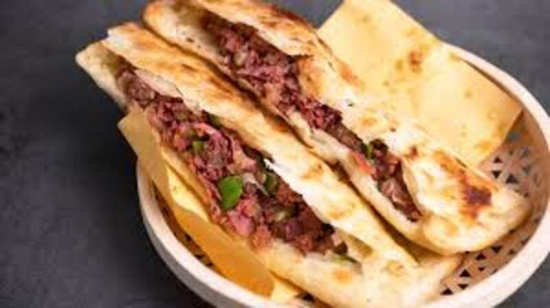 Đậm chất dân dã không kém là bánh nướng kẹp thịt hầm – món ăn từng gắn liền với bữa sáng của người Bắc Kinh xưa. Thịt heo được hầm mềm, tẩm ướp đậm vị rồi kẹp trong bánh nướng nóng giòn, mang lại cảm giác chắc bụng và quen thuộc. Ảnh MIA