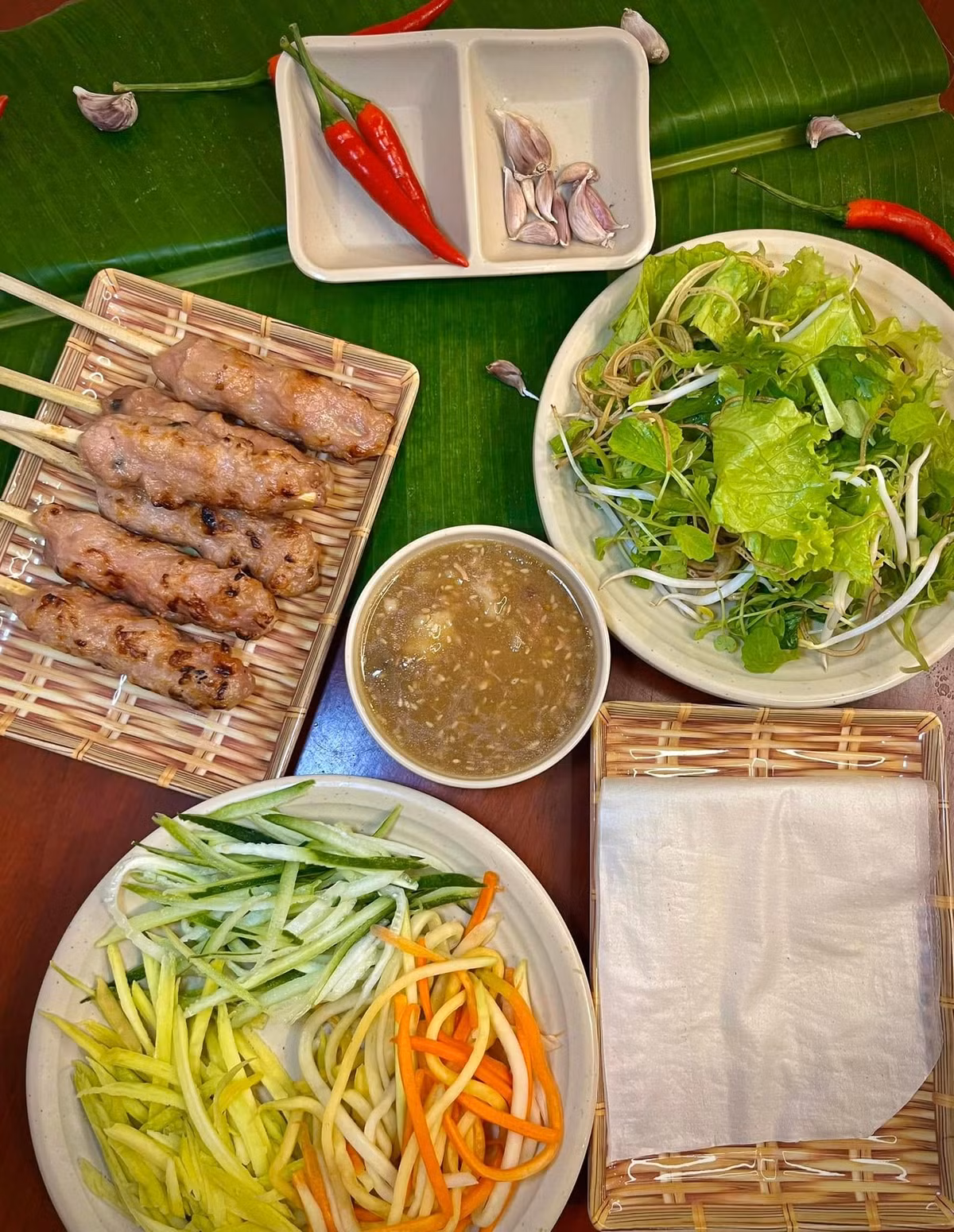 Khi chiều buông, đừng quên ghé quán nem lụi bà Tý trên đường Đào Duy Từ. Nem được nướng trên bếp than hồng, cuốn kèm rau sống, bánh tráng, chuối chát rồi chấm nước lèo đậm đà. Một phần ăn khoảng 25.000 – 40.000 đồng, đủ cho 1–2 người. Hương thơm của thịt nướng quyện cùng vị bùi béo của nước chấm khiến món ăn này trở thành “đặc sản lòng người”. Ảnh Nem lụi bà Tý