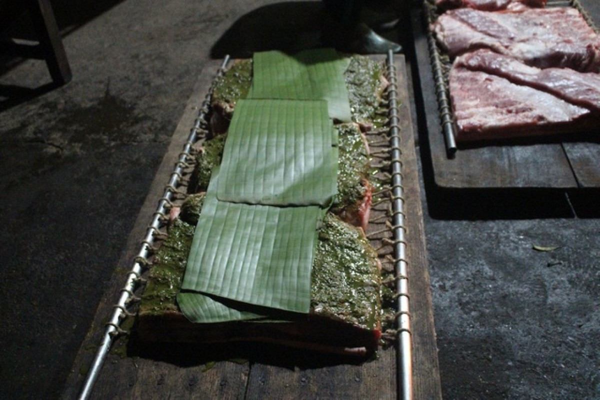Nguyên liệu chính là thịt ba chỉ tươi, có lớp da dày vừa phải, ít mỡ. Thịt được ướp với húng lìu, hạt tiêu, hành tươi, mắm muối và đặc biệt là lá ổi – bí quyết tạo nên hương vị khác biệt. Lá ổi non được băm nhỏ trộn cùng thịt, còn lá bánh tẻ lót bên trong trước khi cuốn chặt quanh đòn tre đã lót lá chuối. Ảnh Đình Châu