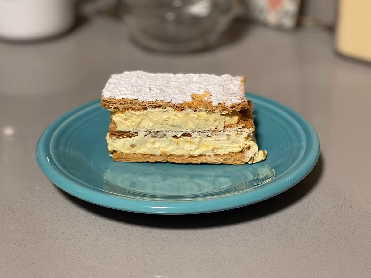 Đối với những người yêu thích bánh ngọt, bánh Napoleon hoàn toàn có thể thử làm tại nhà với các bước cơ bản. Trước tiên là chuẩn bị vỏ bánh puff pastry, gồm bột mì, bơ lạnh, muối và nước. Bột được nhồi kỹ, bơ được cán vào và gấp nhiều lần để tạo lớp ngàn lá, sau đó nướng ở 180–200°C cho đến khi vàng giòn và phồng xốp. Ảnh minh hoạ