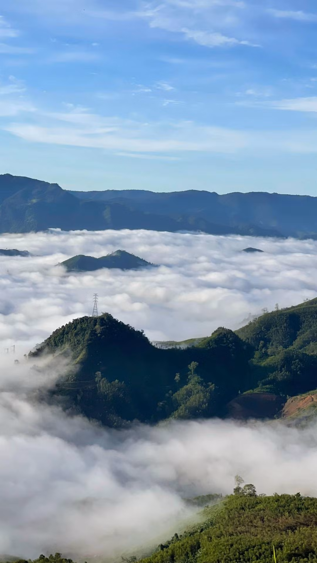 Sương mù, mây trắng từ thung lũng vươn lên ôm lấy đỉnh núi, hòa quyện với ánh bình minh tạo nên một khung cảnh yên bình nhưng không kém phần hùng vĩ. Ảnh Minh Lê