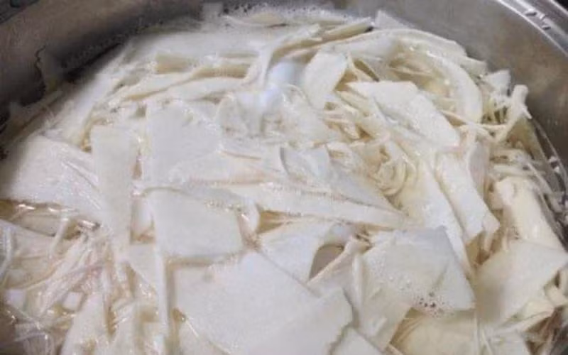 Măng sau khi sơ chế bỏ bẹ già, rửa sạch, cắt miếng mỏng theo chiều dài củ, sẽ được ngâm với nước muối pha loãng và nước vo gạo khoảng 10 giờ hoặc qua đêm để loại bỏ độc tố và giữ độ giòn. Sau đó, măng được rửa sạch, để ráo và ngâm tiếp trong giấm pha nước khoảng 30 phút. Tỏi bóc vỏ, cắt lát, ớt bỏ cuống, thái nhỏ để sẵn sàng ngâm cùng măng. Ảnh minh họa