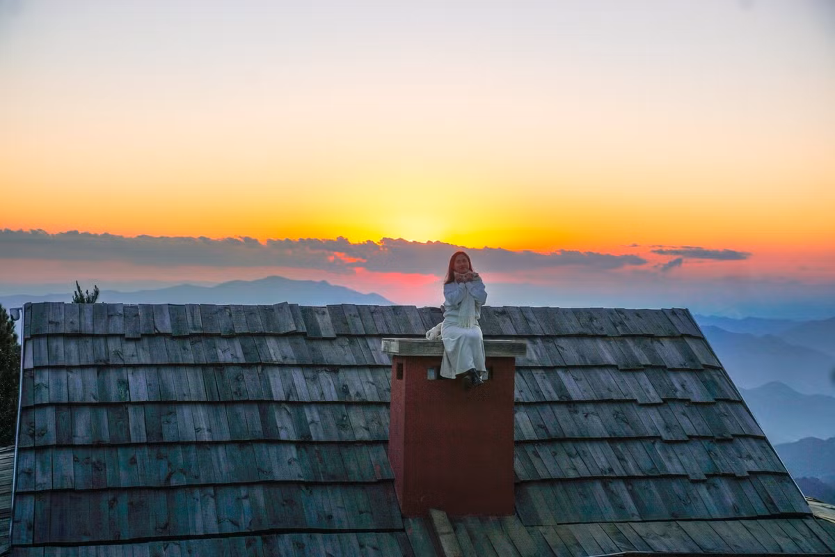 Điểm check-in này nằm tại một quán cà phê nhỏ của người dân địa phương, được xây dựng tận dụng địa hình tự nhiên. Phần mái gỗ nhô ra phía thung lũng, mở ra tầm nhìn thoáng rộng, nơi mây thường xuyên cuộn trào vào buổi sáng sớm hoặc lững lờ trôi khi chiều xuống.