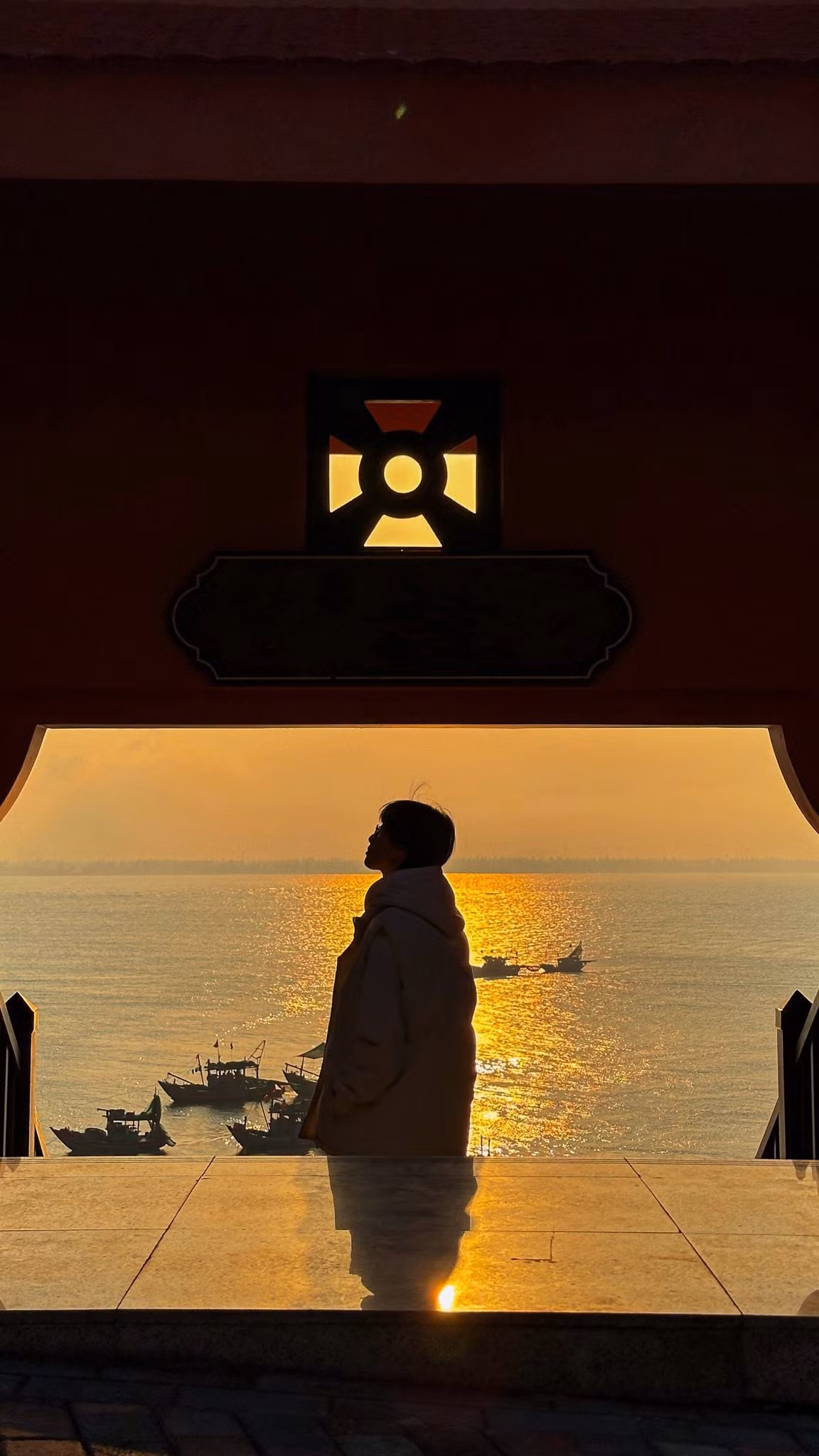 Khi chiều dần buông, mặt trời chậm rãi hạ thấp phía chân trời, nhuộm cả không gian trong gam màu vàng cam dịu nhẹ. Ánh nắng cuối ngày trải dài trên mặt nước, tạo nên những vệt sáng lấp lánh như dải lụa óng ánh. Không gian khi ấy dường như chậm lại, chỉ còn tiếng sóng vỗ nhè nhẹ và làn gió biển mát lành.