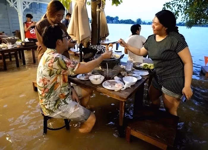 Theo hãng AP, mưa lớn kéo dài suốt hơn một tuần khiến nước sông dâng cao và tràn vào khu vực nhà hàng. Thay vì đóng cửa, chủ quán quyết định tiếp tục phục vụ và bất ngờ thu hút đông đảo thực khách muốn trải nghiệm cảm giác “ẩm thực giữa dòng nước”. Ảnh Associated Press