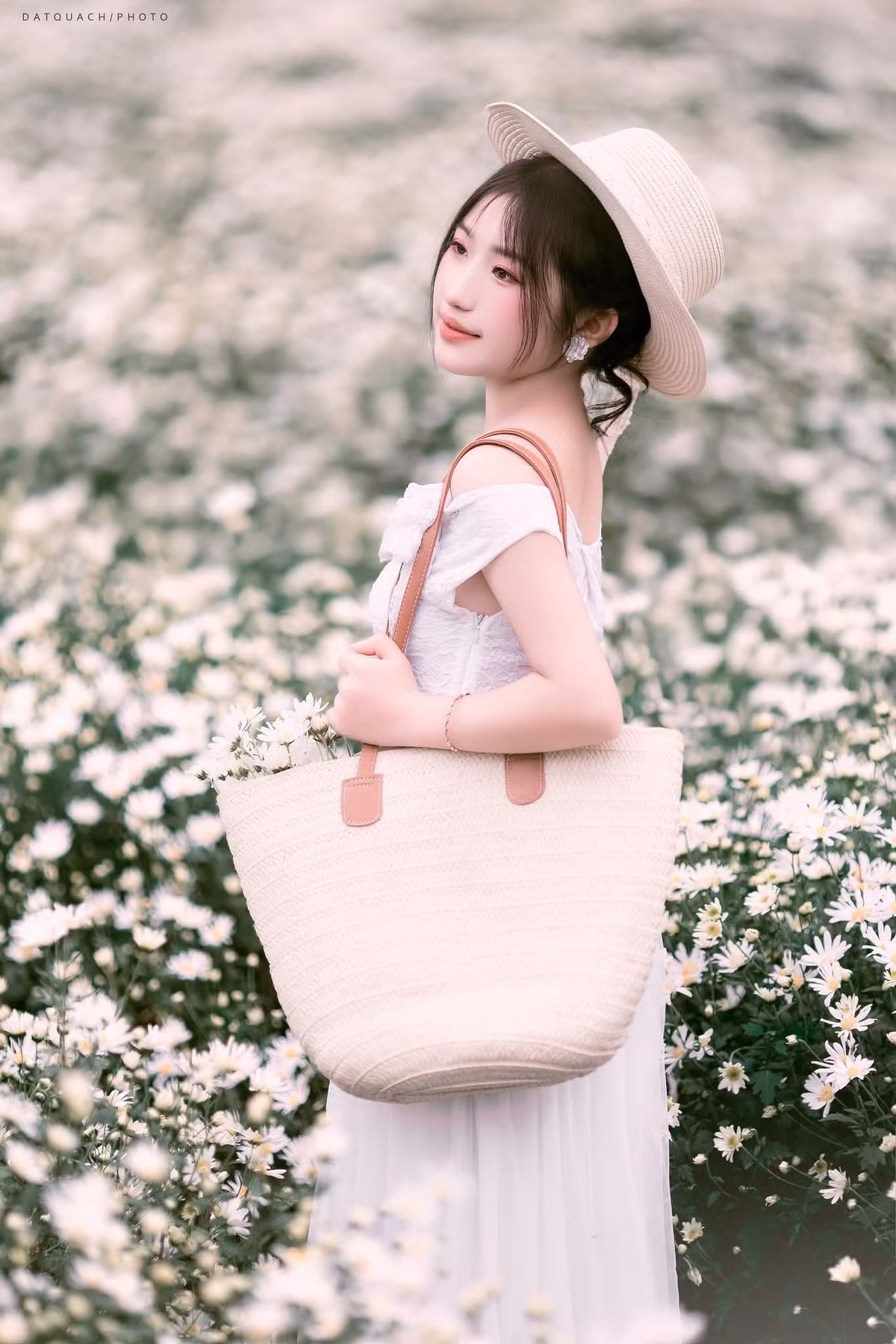 Trang phục để chụp ảnh với cúc họa mi cũng được gợi ý theo hướng nhẹ nhàng và tinh tế. Một chiếc váy pastel – hồng phớt, xanh nhạt hay tím lilac – luôn giúp du khách hòa vào vẻ mềm mại của hoa. Áo dài trắng mang đến nét thanh lịch, cổ điển và rất hợp với phông nền trắng muốt. Ảnh Dat Quach