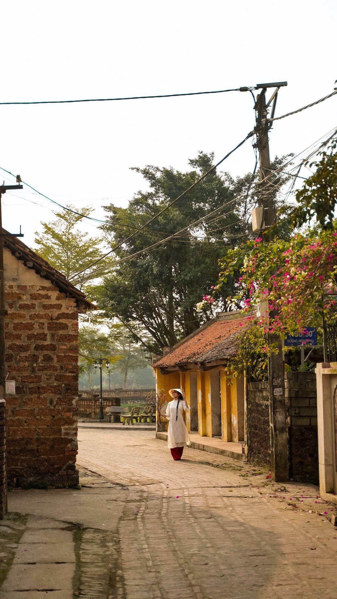 Dạo bước trong làng vào thời điểm này, du khách dễ dàng bắt gặp sắc hoa điểm xuyết trước hiên nhà, những con ngõ nhỏ vắng người và ánh nắng dịu nhẹ phủ lên từng mảng tường đá ong. Chính sự mộc mạc ấy trở thành phông nền lý tưởng cho các bộ ảnh áo dài truyền thống.