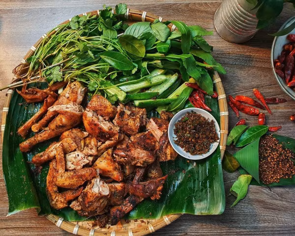 Sau hành trình khám phá những món ăn “thử thách”, du khách có thể tìm đến các món dễ ăn và phổ biến hơn. Gà nướng lá mắc mật là món không thể thiếu trong bữa tiệc vùng cao. Gà ta thả đồi được tẩm ướp với mắc khén, gừng, tiêu rừng, lá mắc mật rồi nướng trên than hồng. Khi chín, da vàng óng, thịt ngọt đậm, chấm cùng muối chẳm chéo cay nồng là đúng điệu Tây Bắc. Ảnh Vietjet