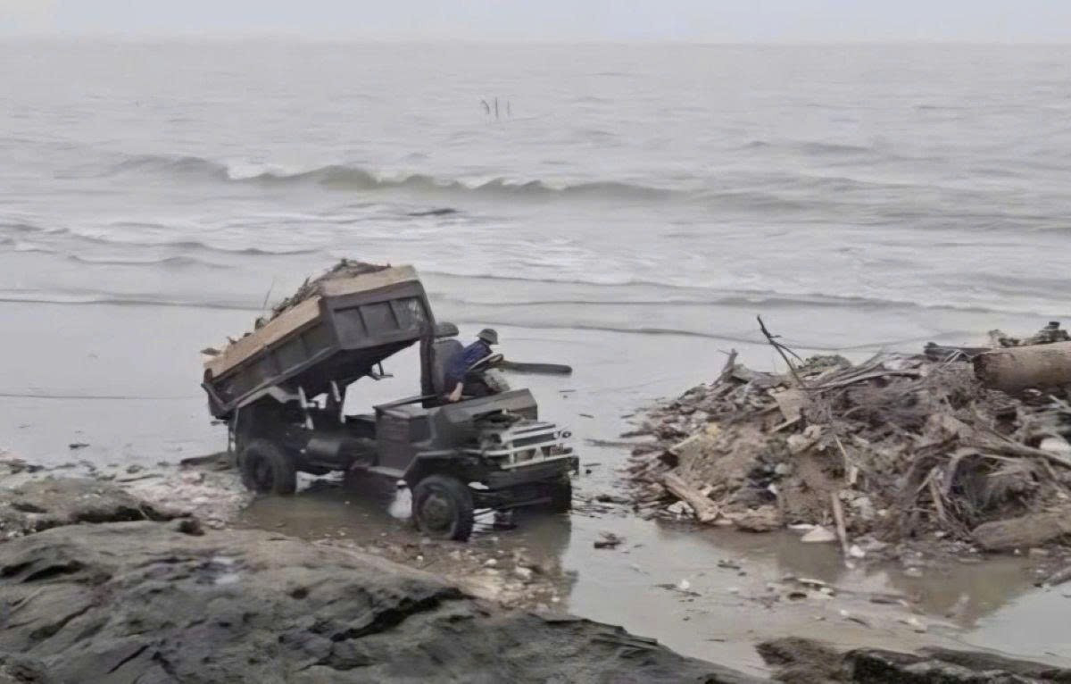 Hình ảnh chiếc xe chở rác đổ ra bãi biển.