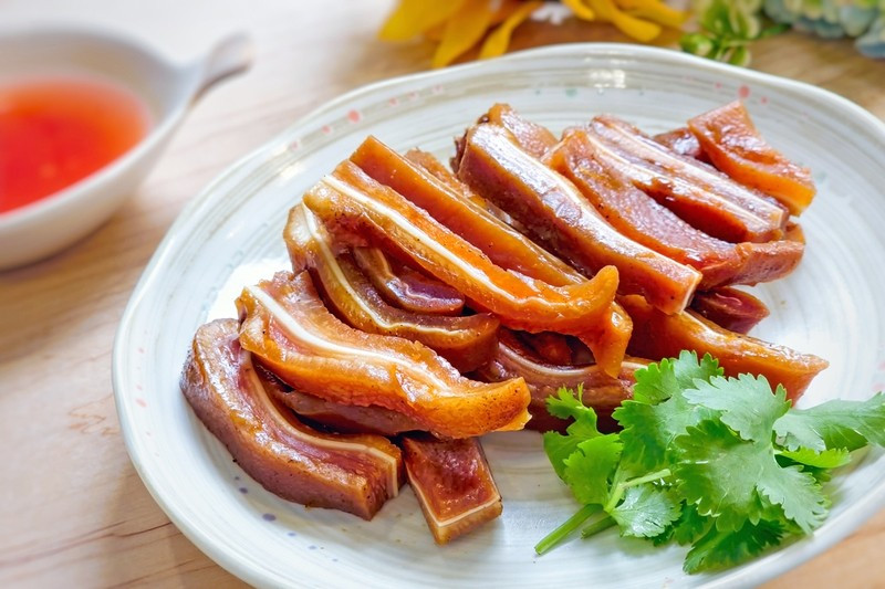 Thay vì luộc chấm mắm gừng quen thuộc, tai heo khi ngâm nước tương lại mang đến trải nghiệm mới mẻ. Tai heo luộc chín, thái mỏng rồi ngâm cùng nước tương pha sẵn, thêm hành tây, cà rốt và dưa leo để tạo độ cân bằng. Sau một ngày ướp lạnh, món ăn đạt độ giòn, thấm vị, rất thích hợp làm món nhắm hoặc ăn kèm cơm nóng. Ảnh minh họa