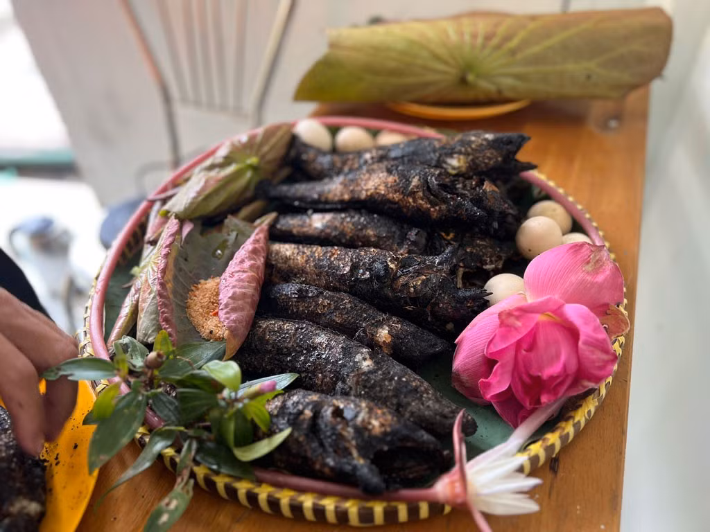 Cá để nguyên con, không đánh vảy, không mổ bụng, xiên qua cây tre tươi rồi nướng trực tiếp trên rơm rạ. Ảnh dulichvietnam