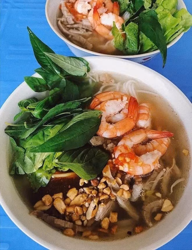Thịt và tôm sau khi luộc sẽ được xếp lên trên bún tươi đã trụng nóng, thêm rau sống như giá, húng quế, xà lách, rồi chan nước dùng nóng lên. Hành phi vàng ruộm, vài lát ớt đỏ, chút mắm nguyên chất đi kèm sẽ làm dậy mùi và hoàn thiện món ăn. Ảnh MIA