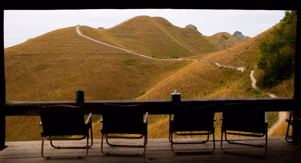 Từ đỉnh đồi, tầm nhìn mở rộng ra toàn cảnh bản làng thấp thoáng bên dưới, những thửa ruộng, dãy núi xanh ôm trọn thảm cỏ trải dài, khiến bất kỳ bức hình nào cũng đủ sức “triệu like”.