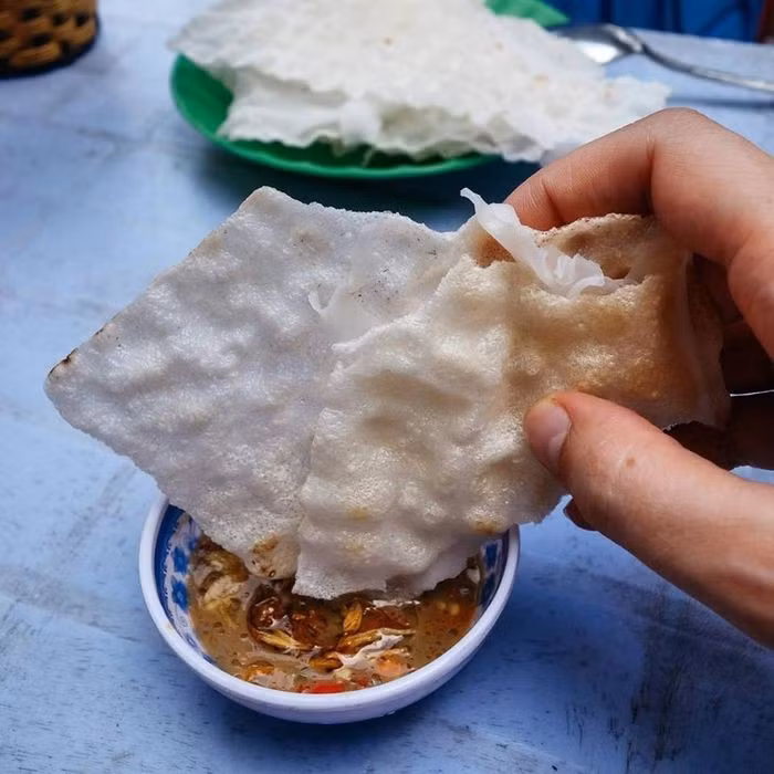 Dù có mặt ở nhiều tỉnh miền Trung, nhưng để thưởng thức bánh tráng đập đúng điệu, du khách nên ghé Hội An (Quảng Nam) – nơi được xem là “thủ phủ” của món ăn này. Tại đây, bánh được làm từ gạo quê xay mịn, nướng ngay tại chỗ, còn mắm nêm thì có công thức riêng, đủ vị mặn – ngọt – cay. Một số quán nổi tiếng như: quán Bà Già (Cẩm Nam), quán bánh tráng đập ven sông Hoài, hoặc các hàng quán trong chợ Hội An. Ảnh amthuc