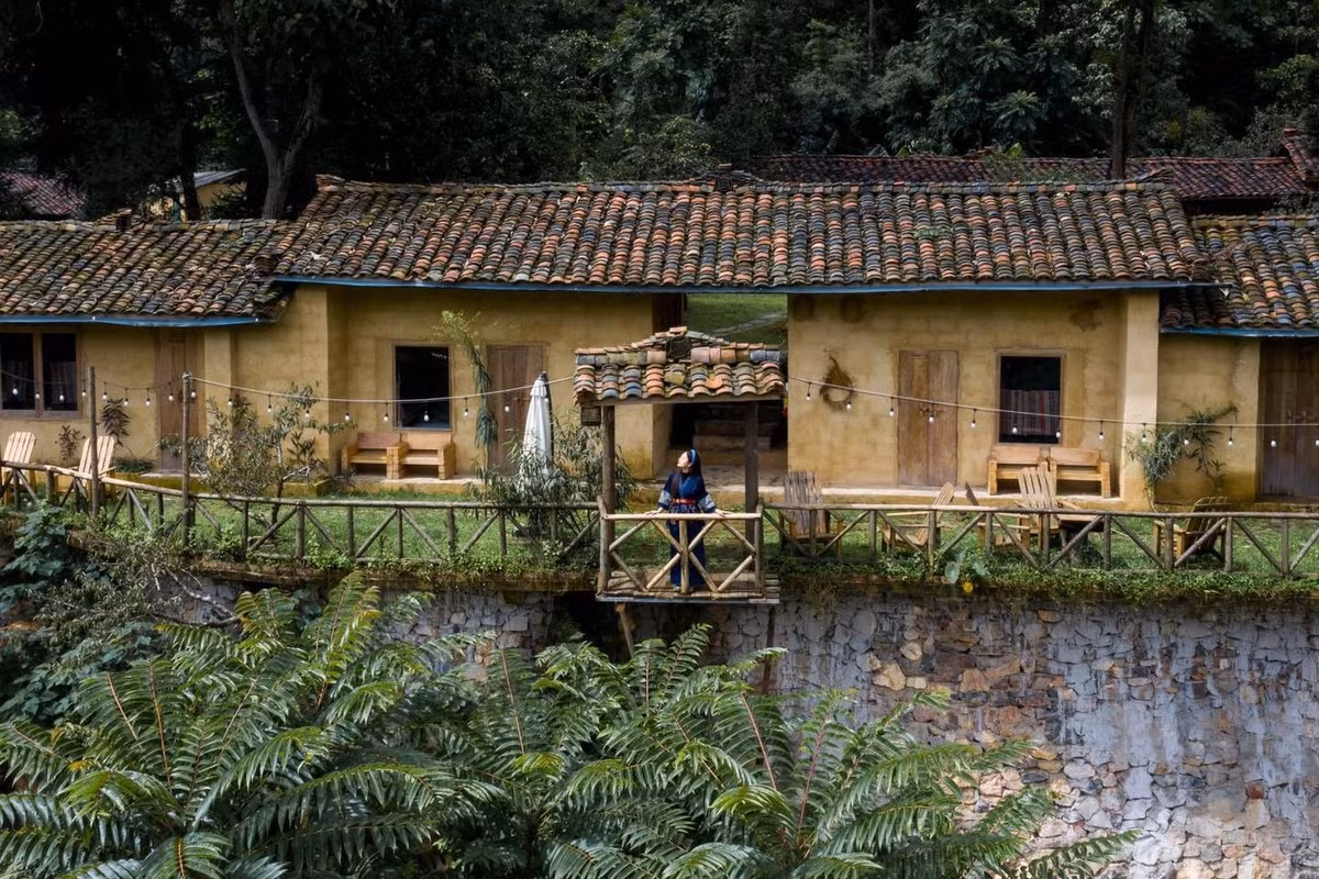 Du khách đến đây có thể đi dạo quanh làng khi sương còn giăng nhẹ trên các mái nhà, đứng từ khoảng sân đất đỏ nhìn lên cột cờ Tổ quốc bay giữa trời xanh, cảm nhận khoảng cách giữa biểu tượng thiêng liêng và cuộc sống bình dị chỉ cách nhau vài bước chân. Vào mùa xuân, cả ngôi làng như được phủ kín trong sắc hồng của hoa đào, trắng của mận, xen lẫn ánh vàng của ngô phơi trước hiên nhà. Ảnh Hiếu Nguyễn Trần