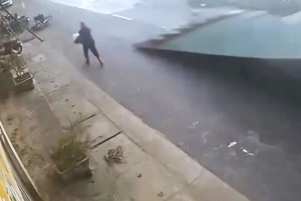 Người phụ nữ nhanh chân chạy thoát trước khi mái tôn lao xuống đường ở xã Vạn An chiều tối 5/10